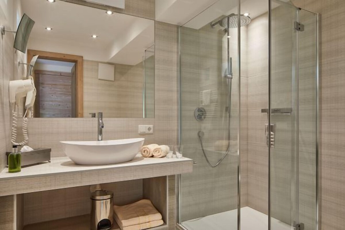 Une salle de bain moderne avec un grand lavabo blanc, une douche en verre et une porte en bois.