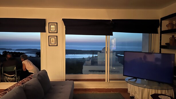 Una sala de estar con una televisión grande, un sofá y vista al océano.