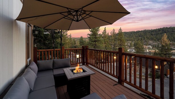 A deck with a sofa, a fire pit, and an umbrella.
