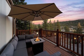 Une terrasse avec un canapé, un foyer extérieur et un parasol.