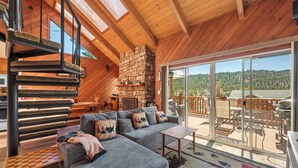 A cozy interior with a sofa, a small table, a fireplace, and a view of the outdoors.