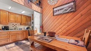A wooden interior with a dining table, chairs, and a kitchen area with wooden cabinets and appliances.