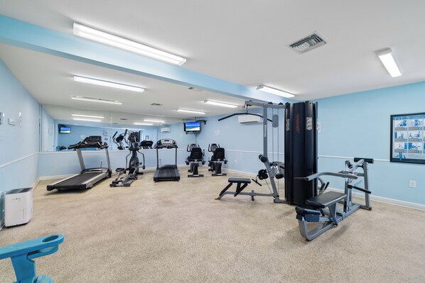 Une salle de sport équipée de tapis de course, de vélos elliptiques et de matériel de musculation.