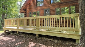 A log cabin with a wooden deck and large windows.