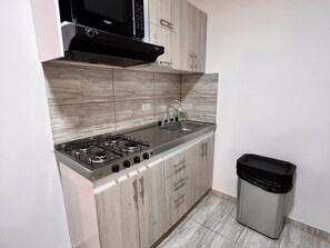 Eine Küche mit Gasherd, Spüle aus Edelstahl und Holzschränken.