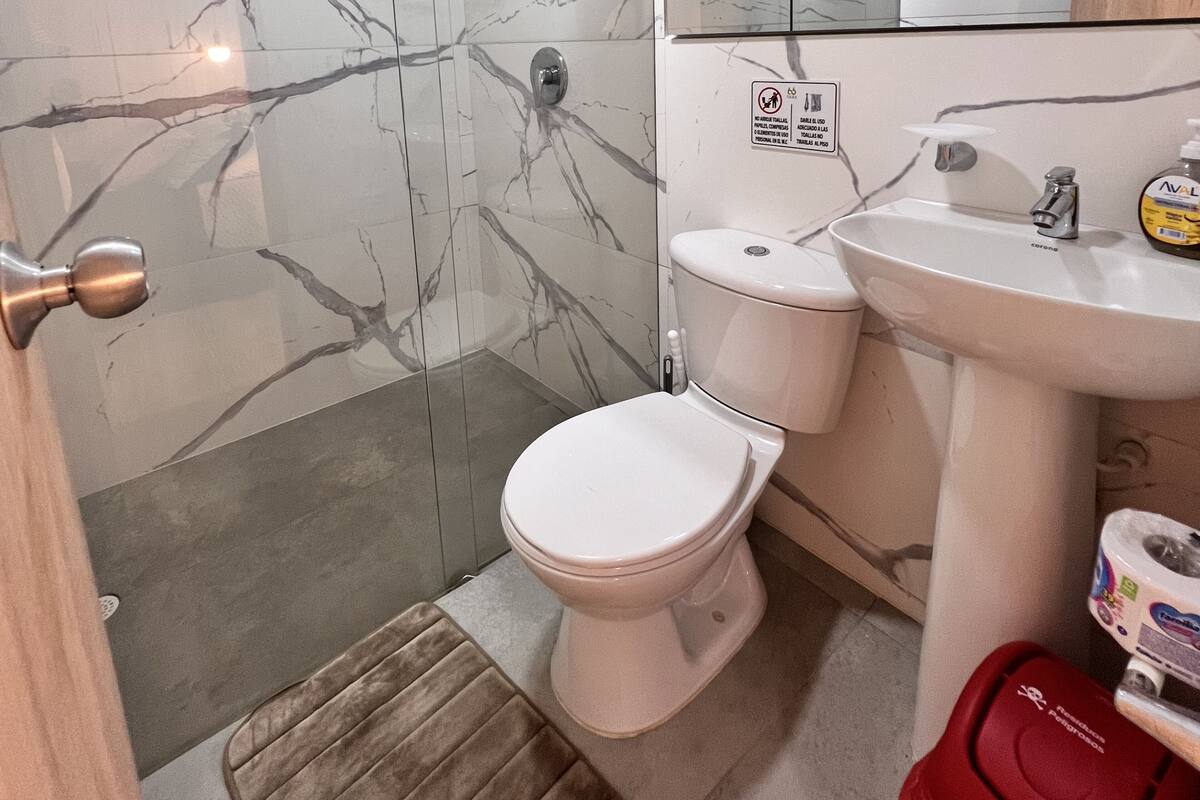Une salle de bain comprenant des toilettes, un lavabo et un espace douche.