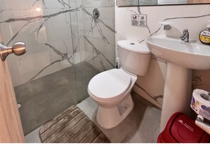 A bathroom with a toilet, sink, and shower area. - Park 66 Apartaestudios (Cali)