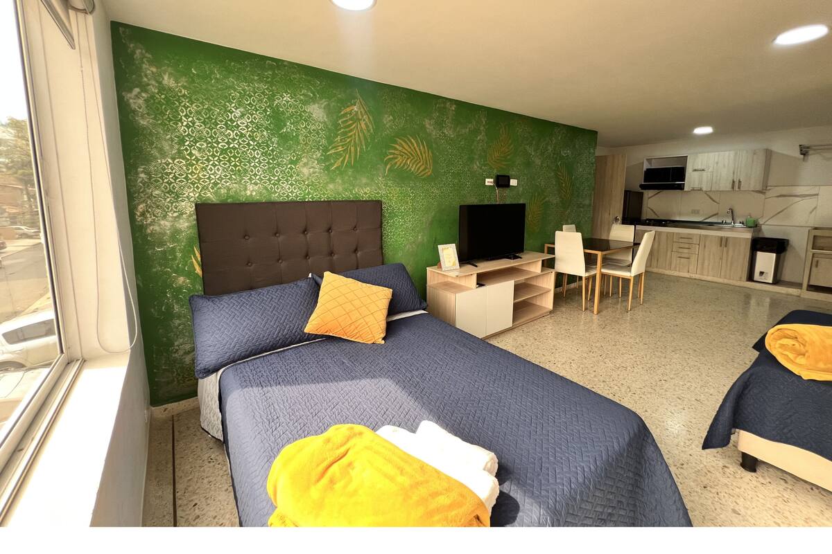 Une chambre d’hôtel comprenant un lit, un bureau avec une télévision, une chaise et une kitchenette.