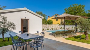 Eine Villa mit Pool, Sitzgelegenheiten im Freien und einer Steinmauer.