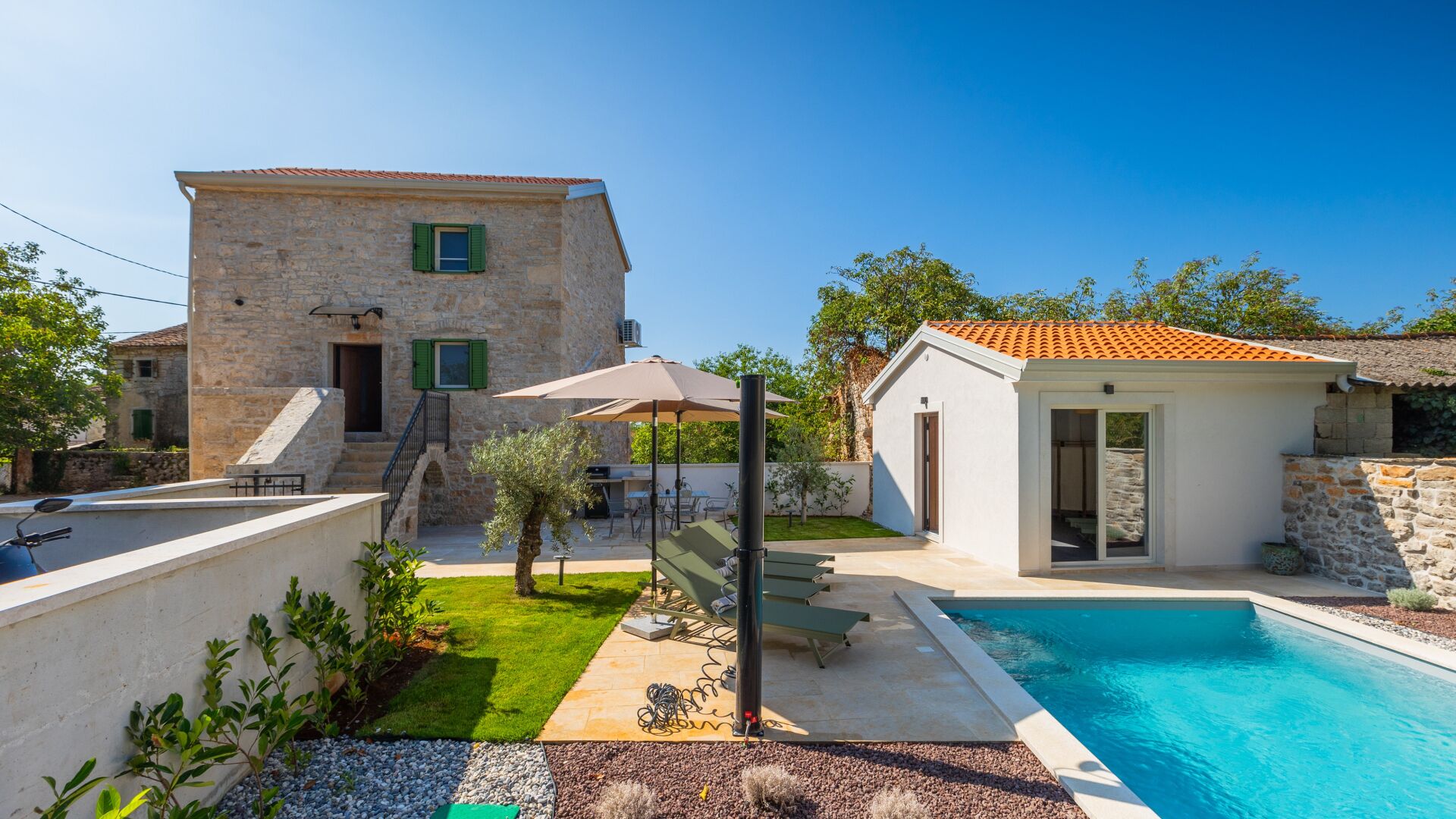 Un bâtiment en pierre doté d’une piscine, d’un espace extérieur aménagé et d’un petit jardin.