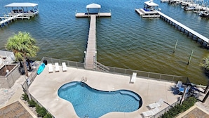 A swimming pool with a deck, lounge chairs, and a dock with boats. - Little Lagoon Cottage for 8 - Free Activities (Gulf Shores)