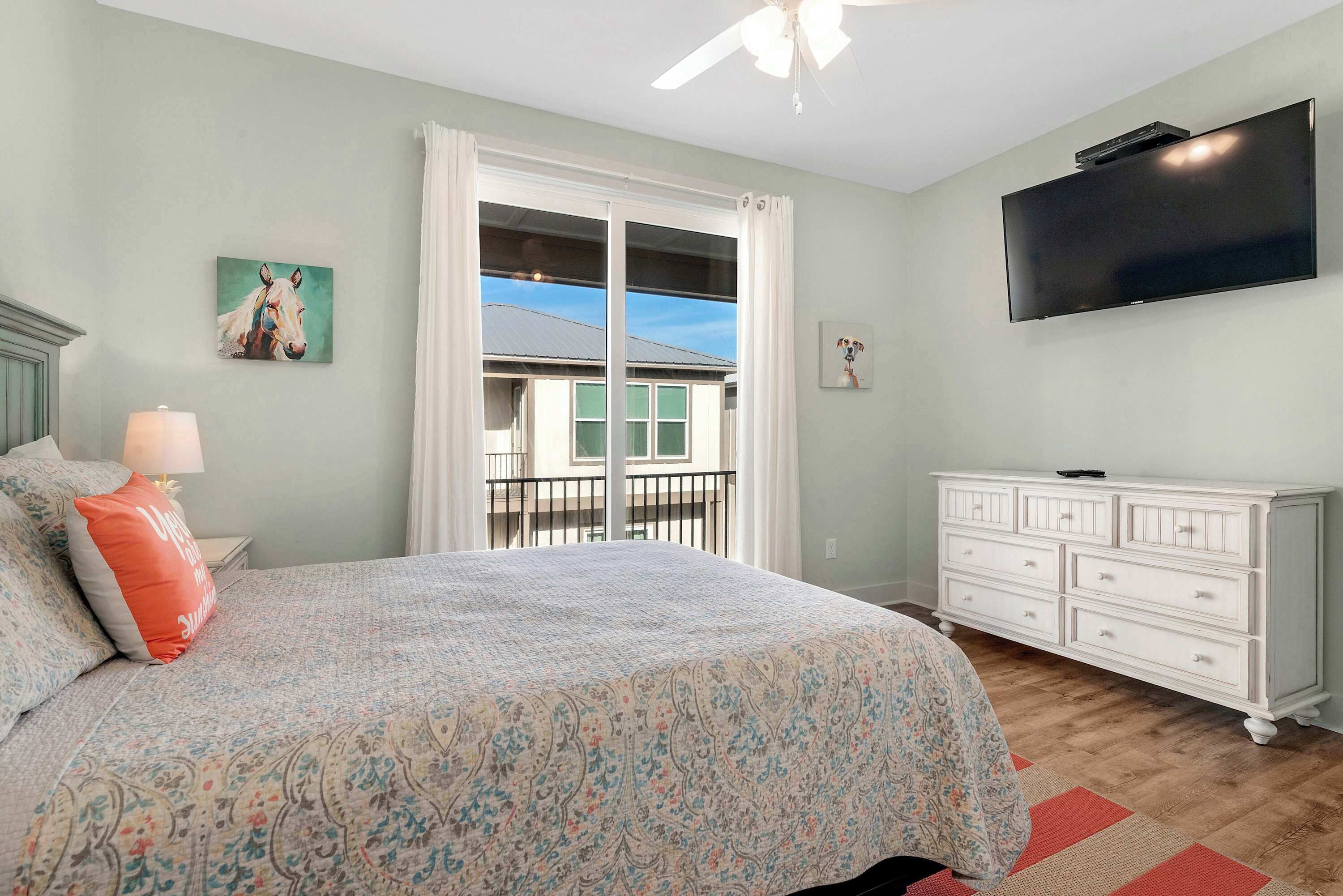 Un dormitorio con cama, cómoda, televisor y balcón con vistas.