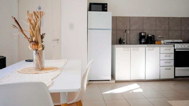 Una cocina moderna con armarios blancos, un refrigerador y un microondas.
