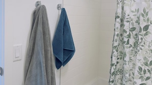 A bathroom with a shower curtain, two towels hanging on a rack, and a bathtub.