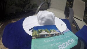 Ein Liegestuhl mit weißem Sonnenschirm, einem Handtuch und einem Strandkissen.