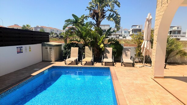 Ein rechteckiger Swimmingpool mit blauen Mosaikfliesen, umgeben von einer gefliesten Terrasse.