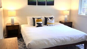 Une chambre avec un grand lit, deux tables de chevet, un luminaire au plafond et une fenêtre.