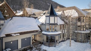 Un quartier résidentiel comprenant plusieurs maisons, dont une demeure imposante dotée d’une structure en forme de tour et d’un balcon.