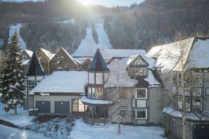A snow-covered residential area with houses featuring steep roofs and a central tower-like structure.