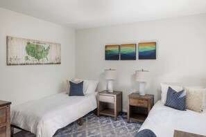 A hotel room with two beds, a map on the wall, and two lamps on wooden nightstands.