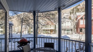 A covered patio with a grill, chairs, and a view of snow-covered houses and mountains. - Smuggler Mine — Modern Pet-Friendly Retreat Near Slopes (Telluride)