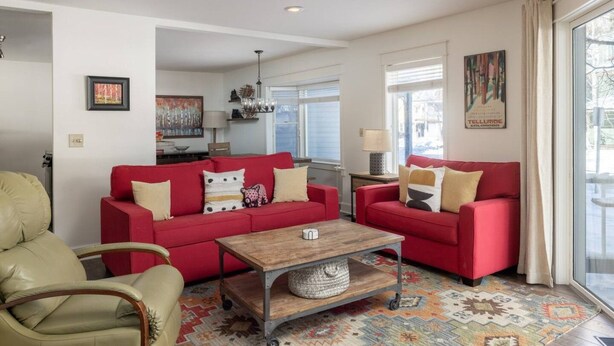 Un salon avec un canapé rouge, une table basse en bois et un tapis à motifs.