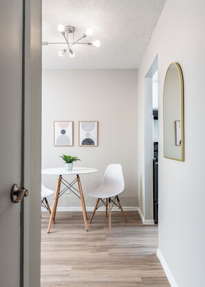 A modern dining area with a round table, two white chairs, a potted plant, and two framed artworks on the wall. - Hyde Park Escape (Austin)