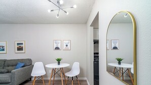 A modern living room with a grey sofa, white chairs, a small round table, and a large mirror. - Hyde Park Escape (Austin)