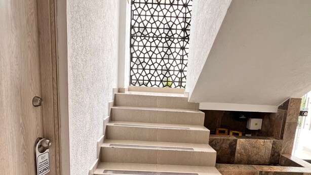 A set of beige stone stairs leading to a landing with a decorative metal grille. - Park 2009 Apartaestudios (Cali)