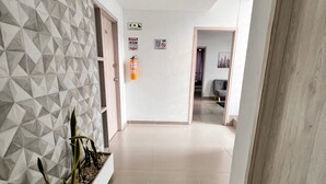 A hallway with a geometric-patterned wall, a fire extinguisher, and emergency exit signs. - Park 2009 Apartaestudios (Cali)