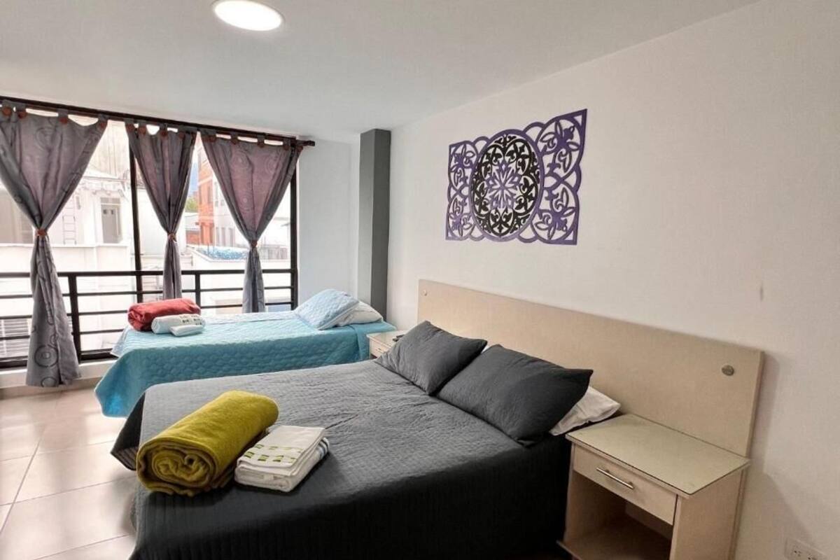 A hotel room with two beds, a desk, and a decorative wall piece.