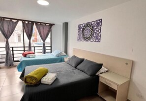A hotel room with two beds, a desk, and a decorative wall piece. - Park 2009 Apartaestudios (Cali)