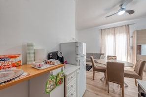 A modern kitchen with a refrigerator, microwave, and a dining area with a table and chairs. - Holiday Home 'Katia' with Private Garden and Air Conditioning (Cellino San Marco)