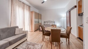 Una sala de estar moderna con un sofá, una mesa de comedor, sillas, un ventilador de techo y un espejo grande.