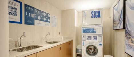 A modern bathroom with a sink, mirror, and a stacked washer and dryer unit.