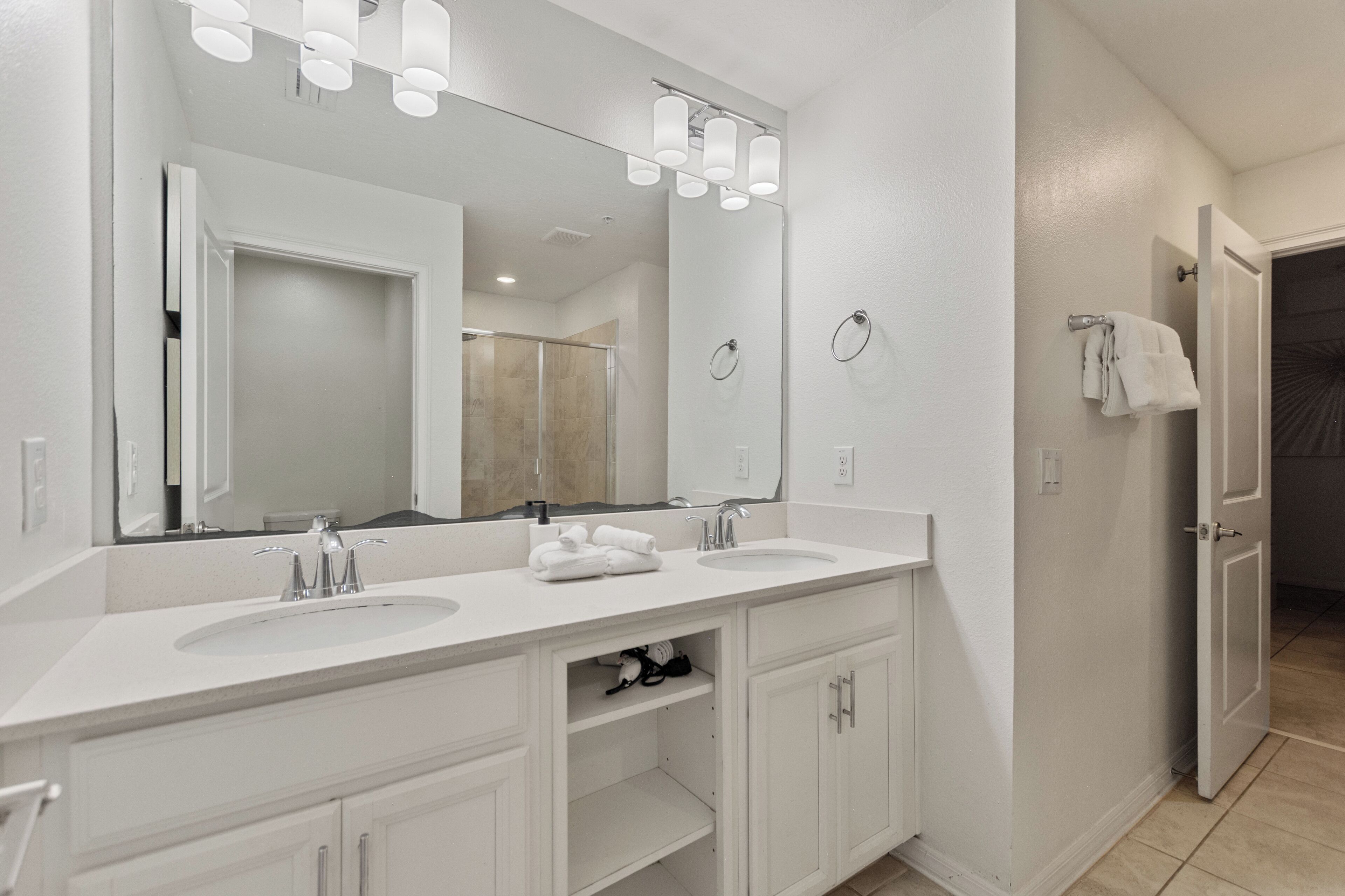 Un baño moderno con dos lavamanos, un espejo grande y una zona de ducha.