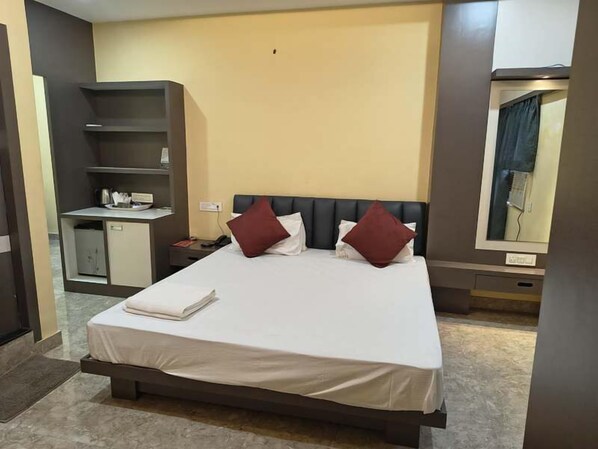 Una habitación de hotel con cama, escritorio, armario y espejo.