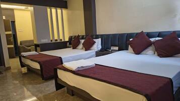 Habitación de hotel con dos camas, cada una con cabecero y almohadas, una mesita de noche y una puerta que da a un baño.