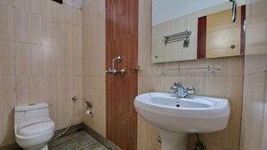 A bathroom with a toilet, sink, and mirror. - HOTEL SIMLA (Siliguri)