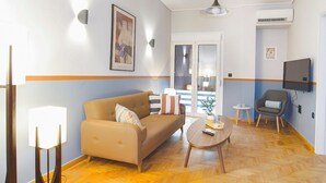 Ein Wohnzimmer mit einer Couch, einem Couchtisch, einem Beistelltisch und einem an der Wand montierten Fernseher.