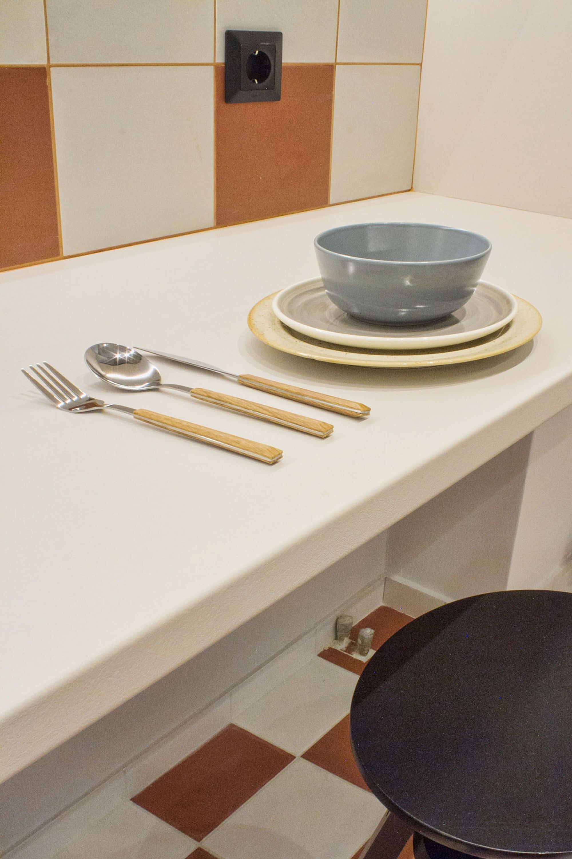 A kitchen counter with a bowl, a spoon, and a fork.