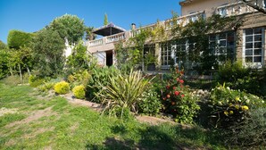 Un jardín con diversas plantas y un edificio con balcón.