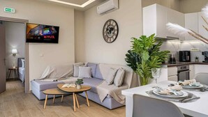 A modern living room with a sofa, a coffee table, and a dining area with a table set for two. - Pietra Cave Suite with private pool (Zakynthos)