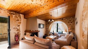 Ein gemütliches Wohnzimmer mit Steinwand, Holzboden und einem Kamin, inklusive Sofa und Fernseher.