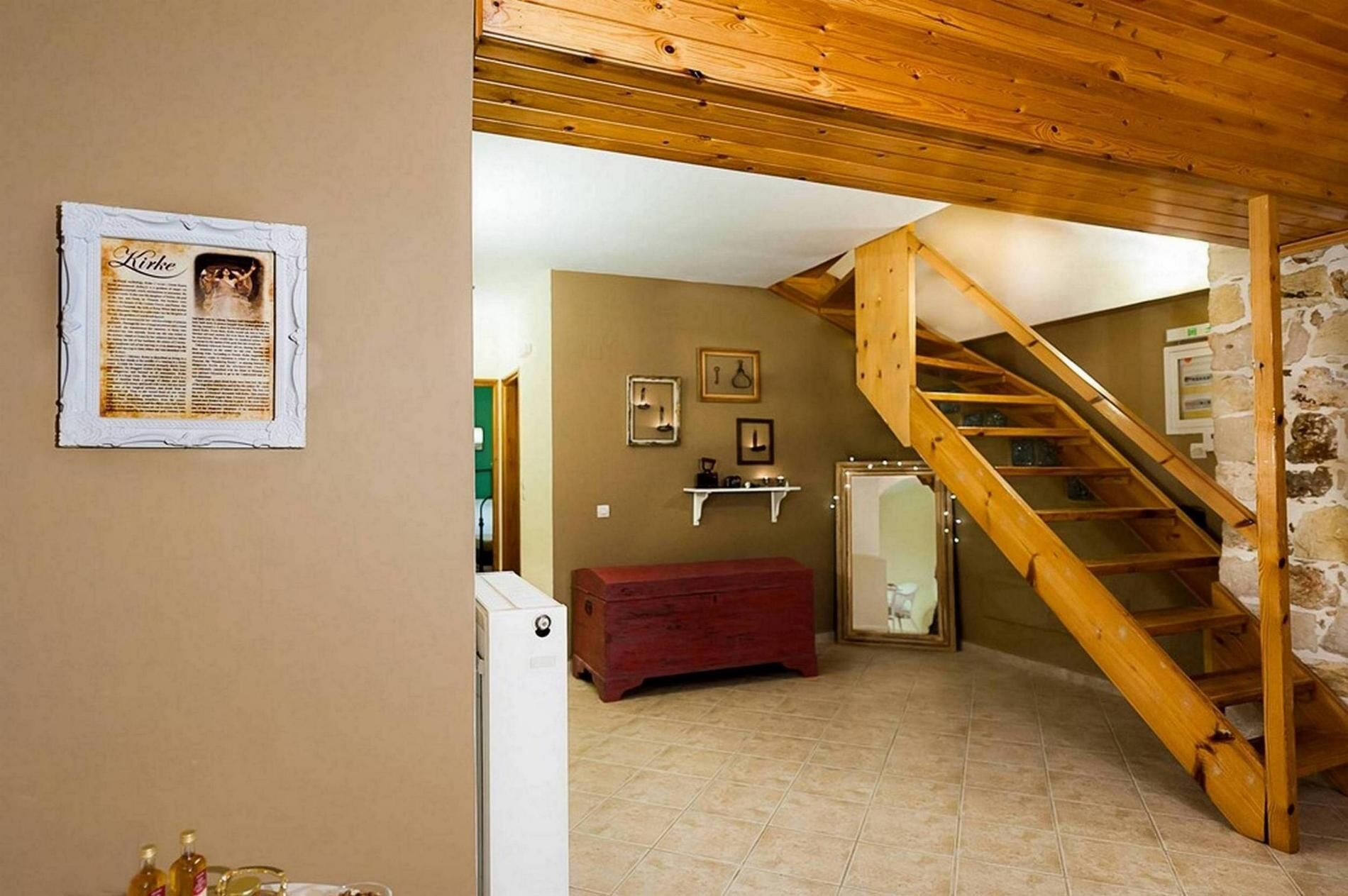 Een kamer met een houten trap, een rode bank en een aan de muur bevestigd fotolijstje.