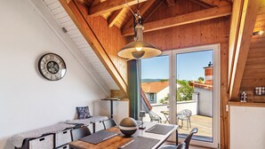A dining area with a wooden table, chairs, a clock, and a view through a glass door. - Apartment 'Männerleben' with Private Terrace and Wi-Fi (Harztor)