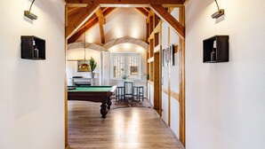 A wooden-floored hallway leading to a billiards room with a pool table, a bar area with stools, and a dining table with chairs. - Apartment 'Männerleben' with Private Terrace and Wi-Fi (Harztor)