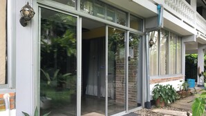 Une maison moderne dotée de grandes portes-fenêtres coulissantes, d’un mur en briques et d’un petit jardin agrémenté de plantes en pot.