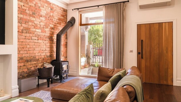 Ein Wohnzimmer mit Backsteinwand, Kamin, Ledersofa und Holztür.