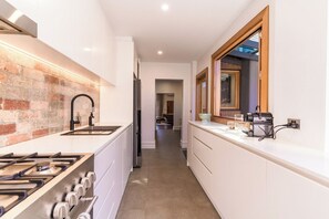 A modern kitchen with a brick accent wall, a gas stove, a sink, and a refrigerator.